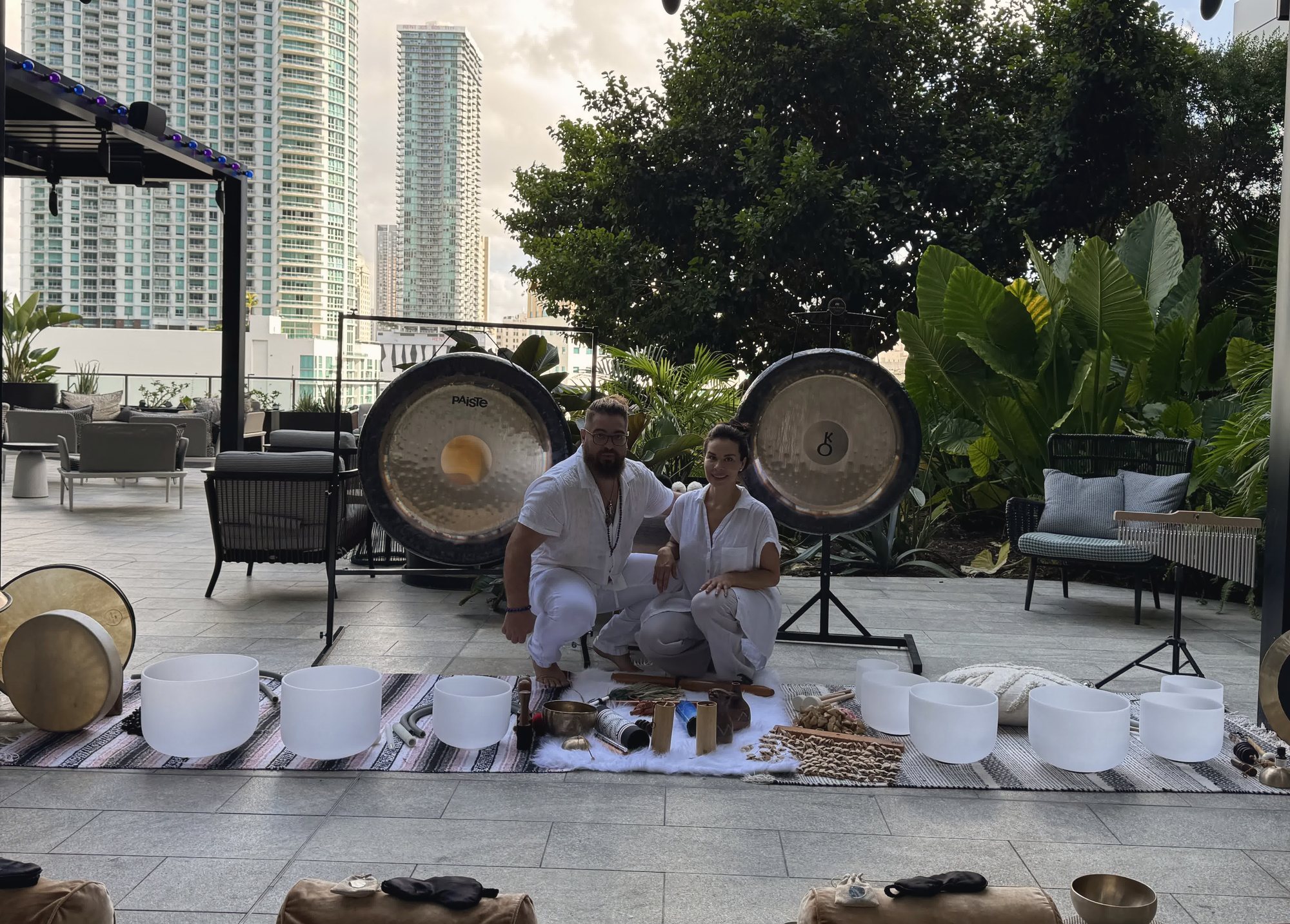 Karina and Juan seated between two gongs on the Puttshack terrace, crystal bowls in front of them